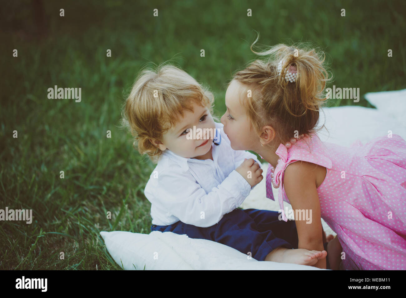 Brother and sister play on summer day outdoor. Girl kiss boy with ...