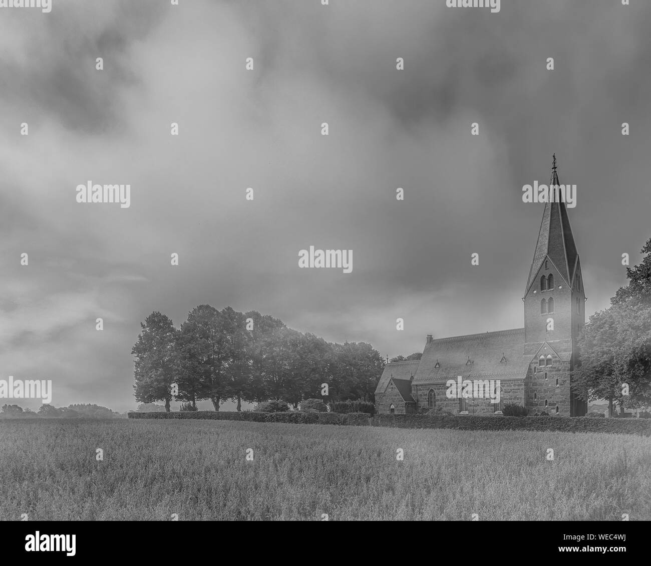 The early morning fog starts to clear at Sonnarslov church in the Skane region of Sweden. Stock Photo