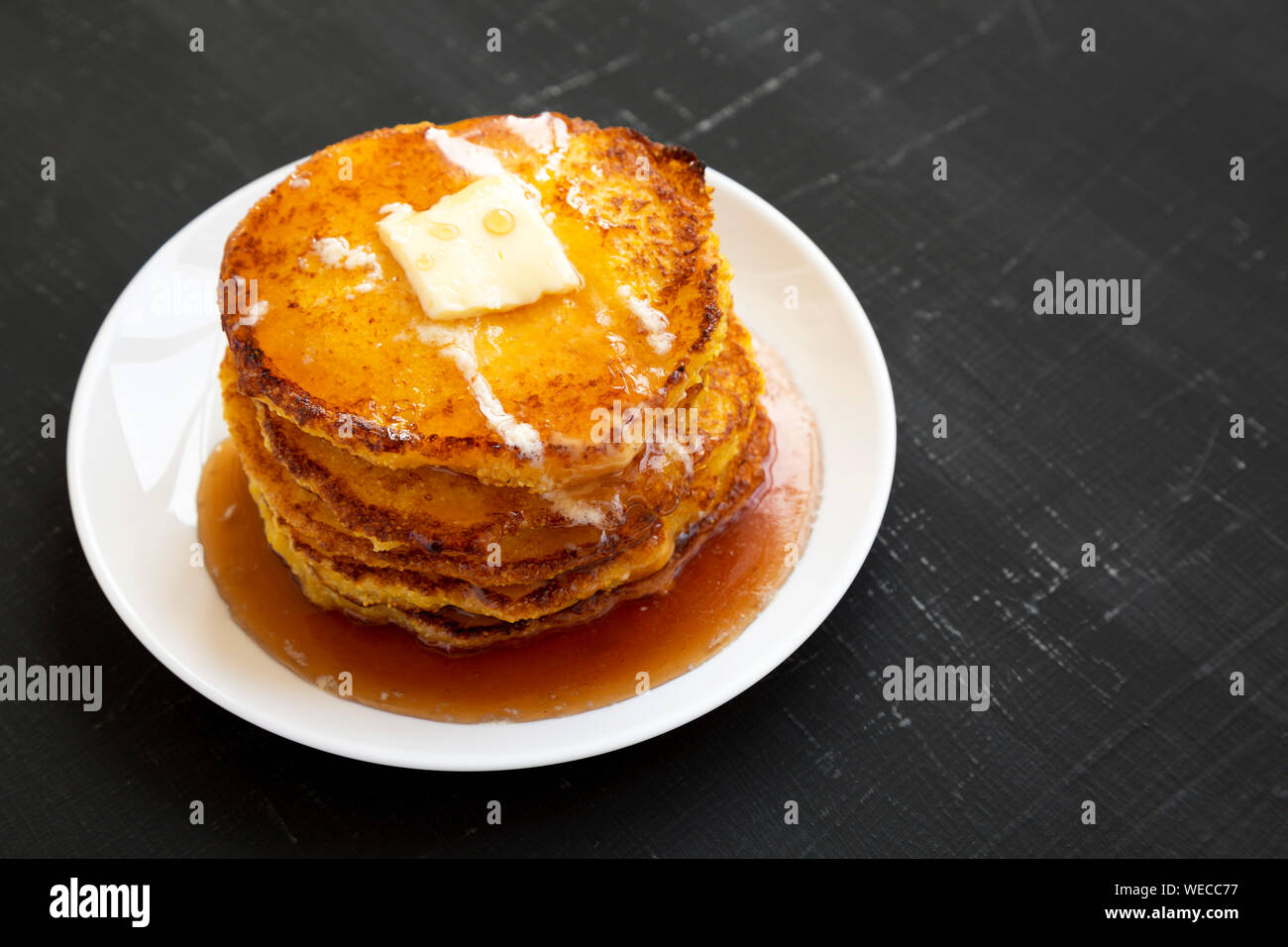 Homemade corn meal Johnny cakes on a white plate on a black background
