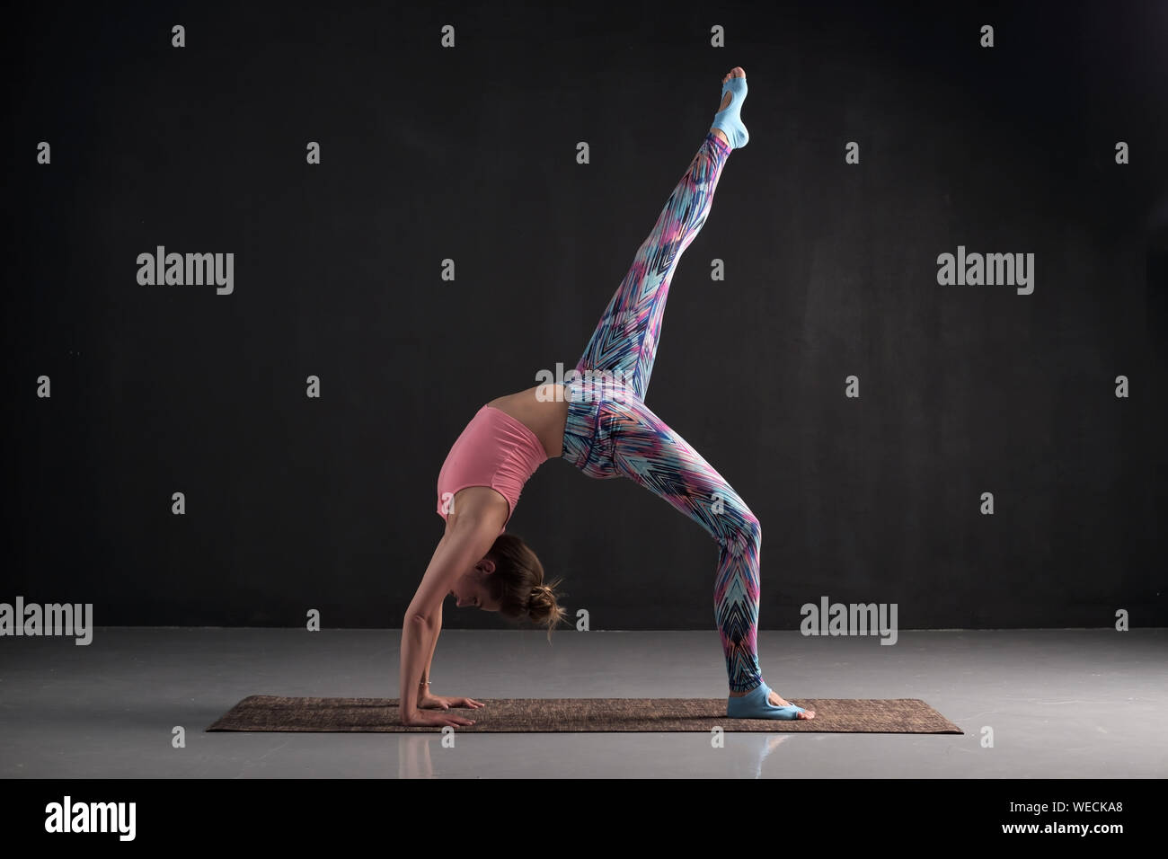 Woman practices yoga asana eka pada chakrasana or dhanurasana or one