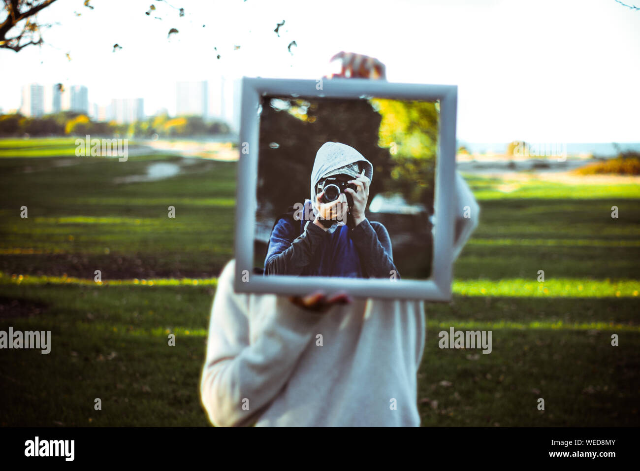 Person Holding Mirror With Reflection Of Man Photographing Through Camera At Park Stock Photo