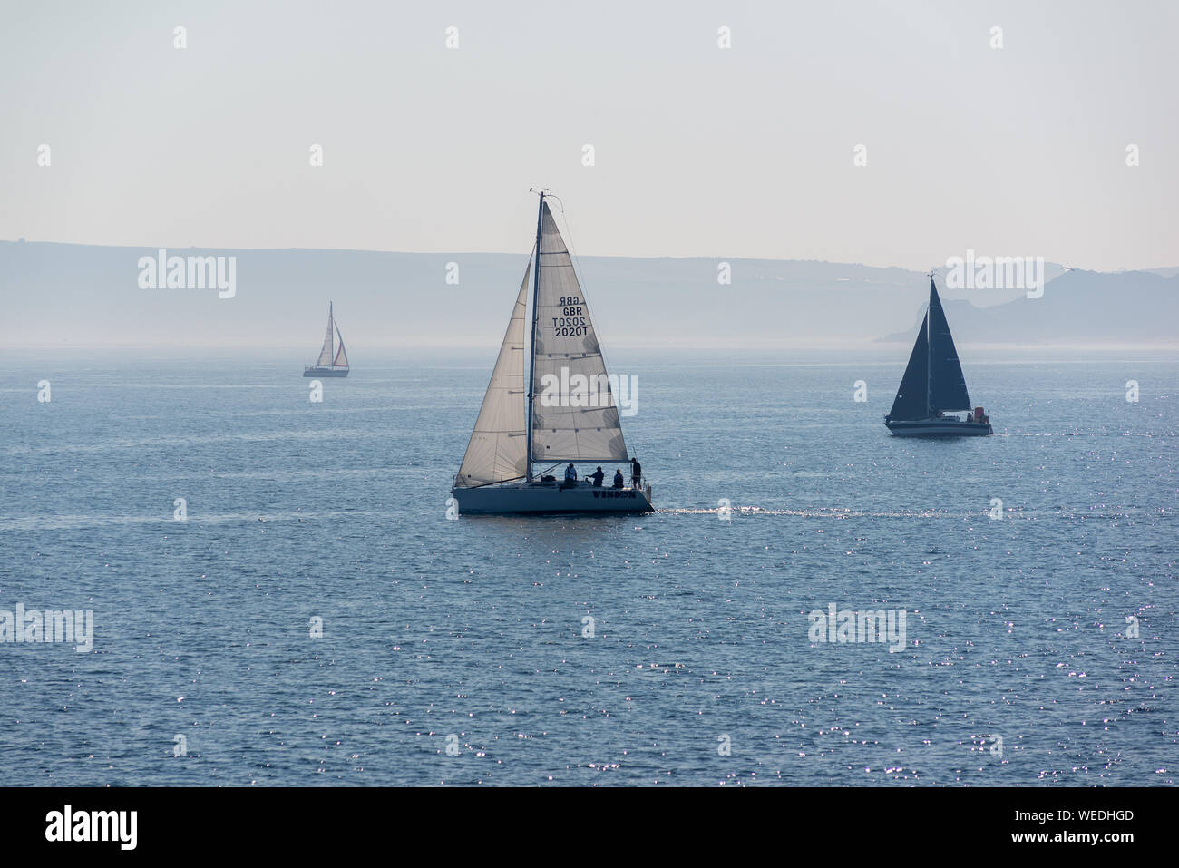 Sail boats off the coast of Scarborough, North Yorkshire, UK, on a calm, hazy summer morning. Stock Photo