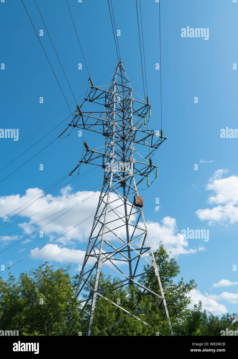 high voltage tower against the blue sky and trees Stock Photo - Alamy