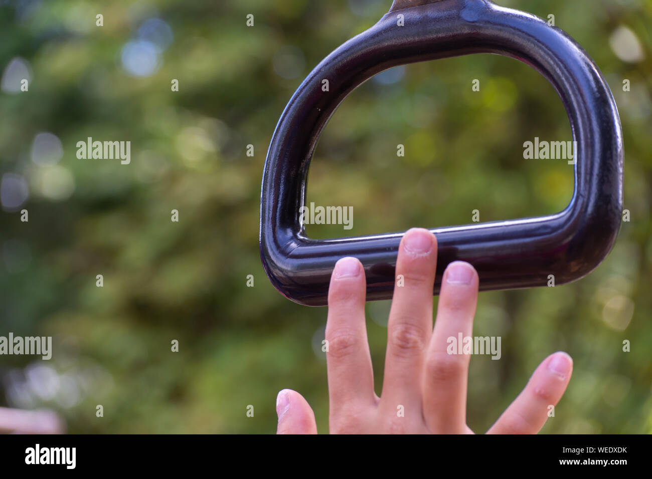 Child's hand nearly achieving goal of grabbing a monkey bar at a