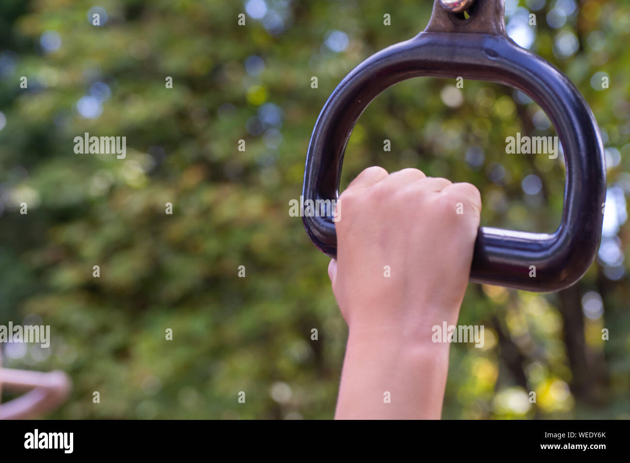 Child's hand grabbing a monkey bar at a playground conecept holding on
