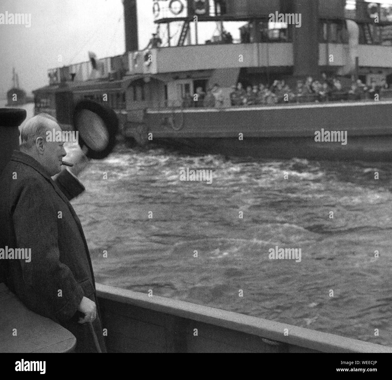 Winston Churchill raises hat to ferryboat passengers passing on the Thames as he inspects damage from German air raids. 25th September 1940 Stock Photo
