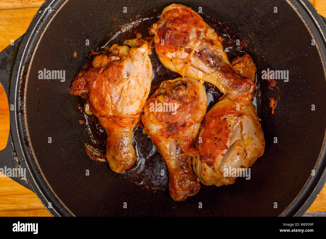 Chicken legs marinated with spices are fried in a cauldron Stock Photo