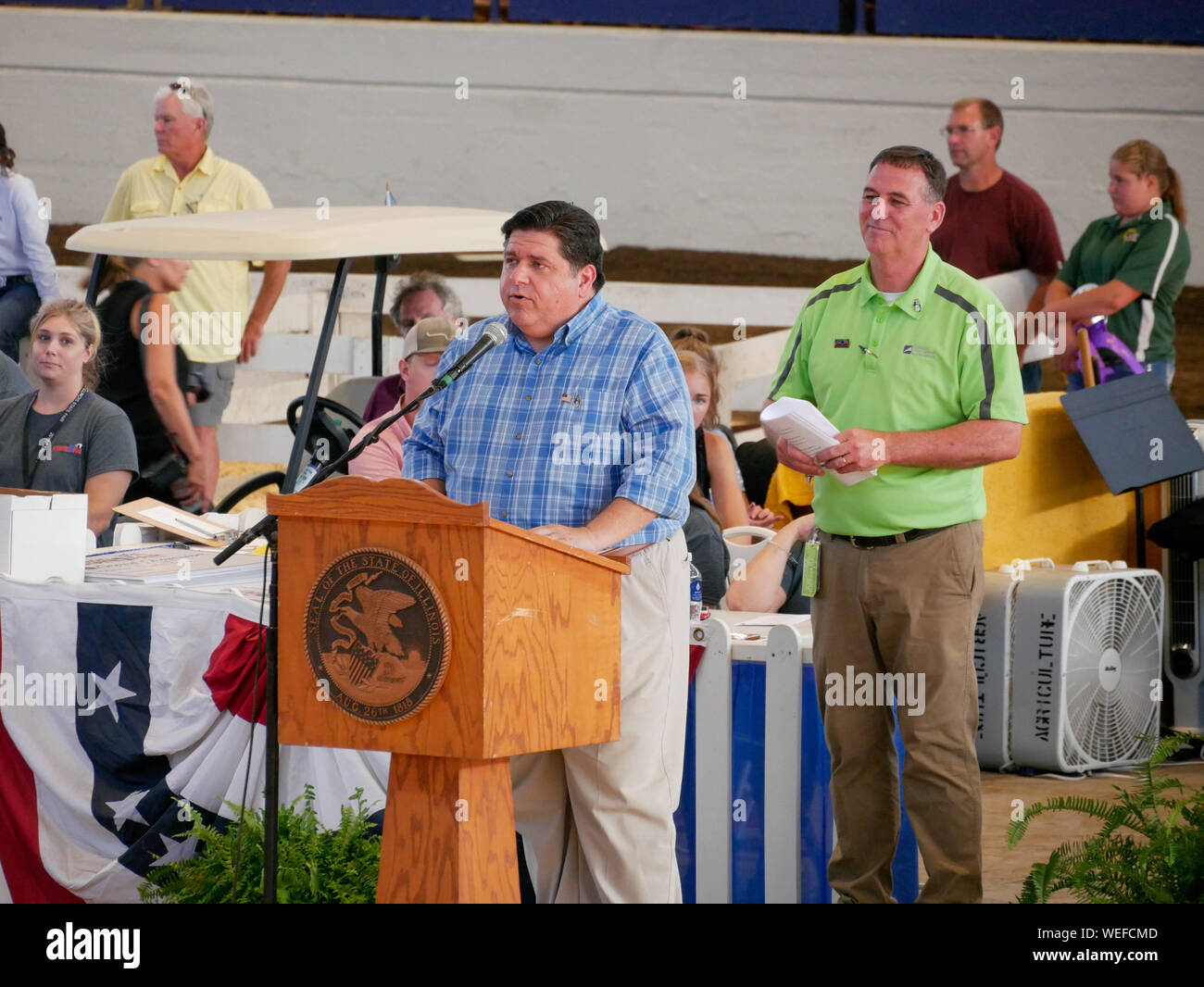 Springfield, Illinois, USA. 13th August 2019. Governor JB Pritzker speaking at the 2019 Illinois State Fair Governor's Sale of Champions. Department of Agriculture Director John Sullivan in green shirt. Stock Photo