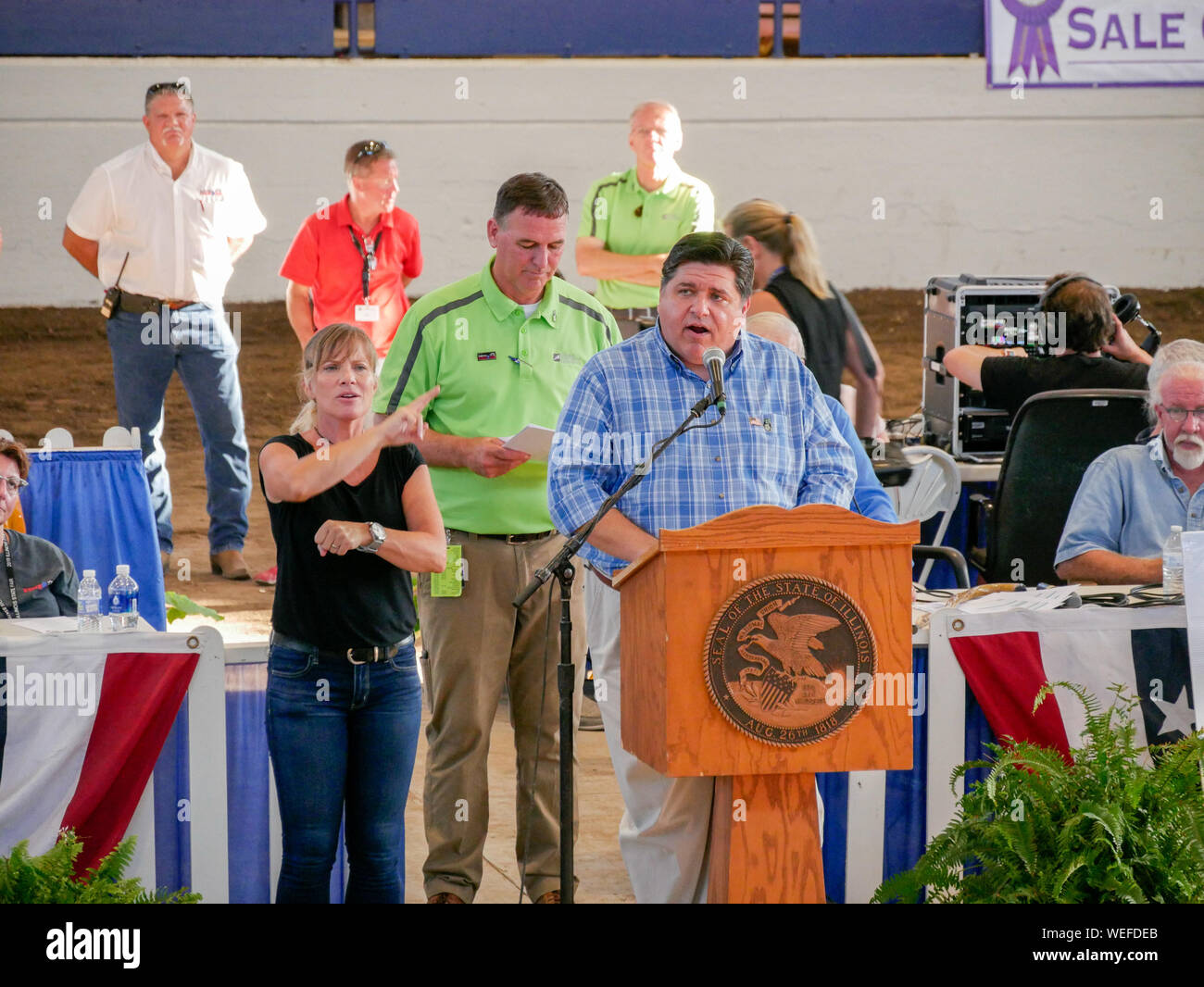 Springfield, Illinois, USA. 13th August 2019. Governor JB Pritzker speaking at the 2019 Illinois State Fair Governor's Sale of Champions. Department of Agriculture Director John Sullivan in green shirt. Stock Photo