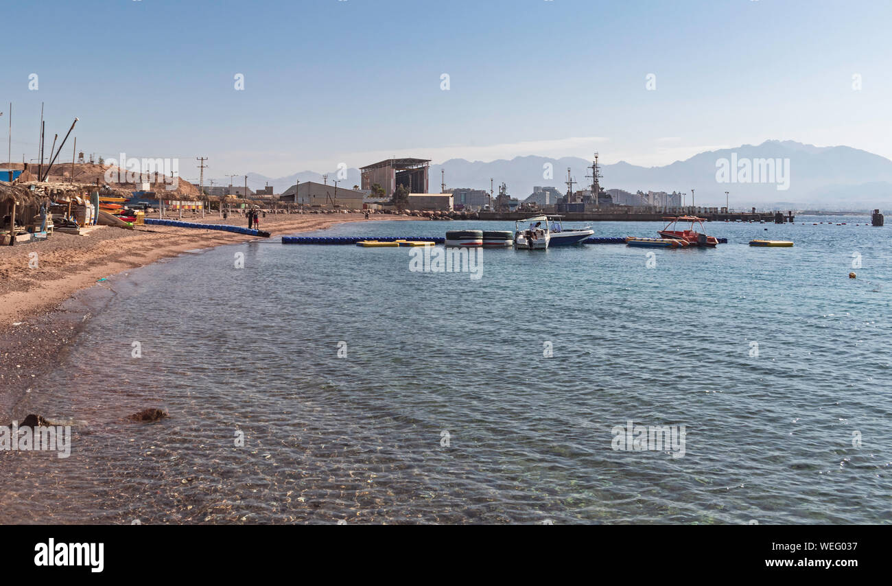 a floating dock and small boats at the sailing and sea sport club near the naval facility and harbor in eilat in israel with hotels in the background Stock Photo