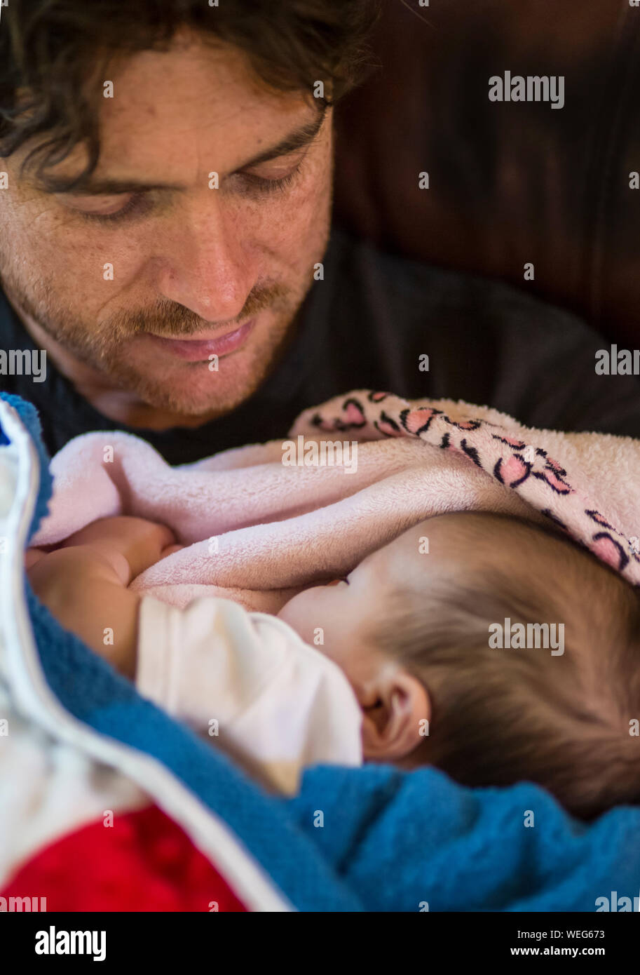 Caucasian father holding and looking at very young baby, close up Stock Photo