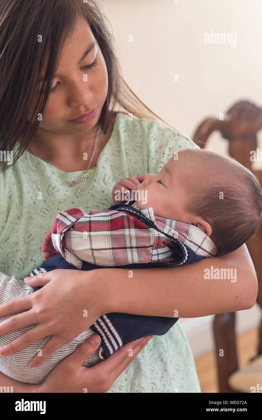 Teenage Asian girl holding baby mixed ethnicity brother, San Jose, California Stock Photo