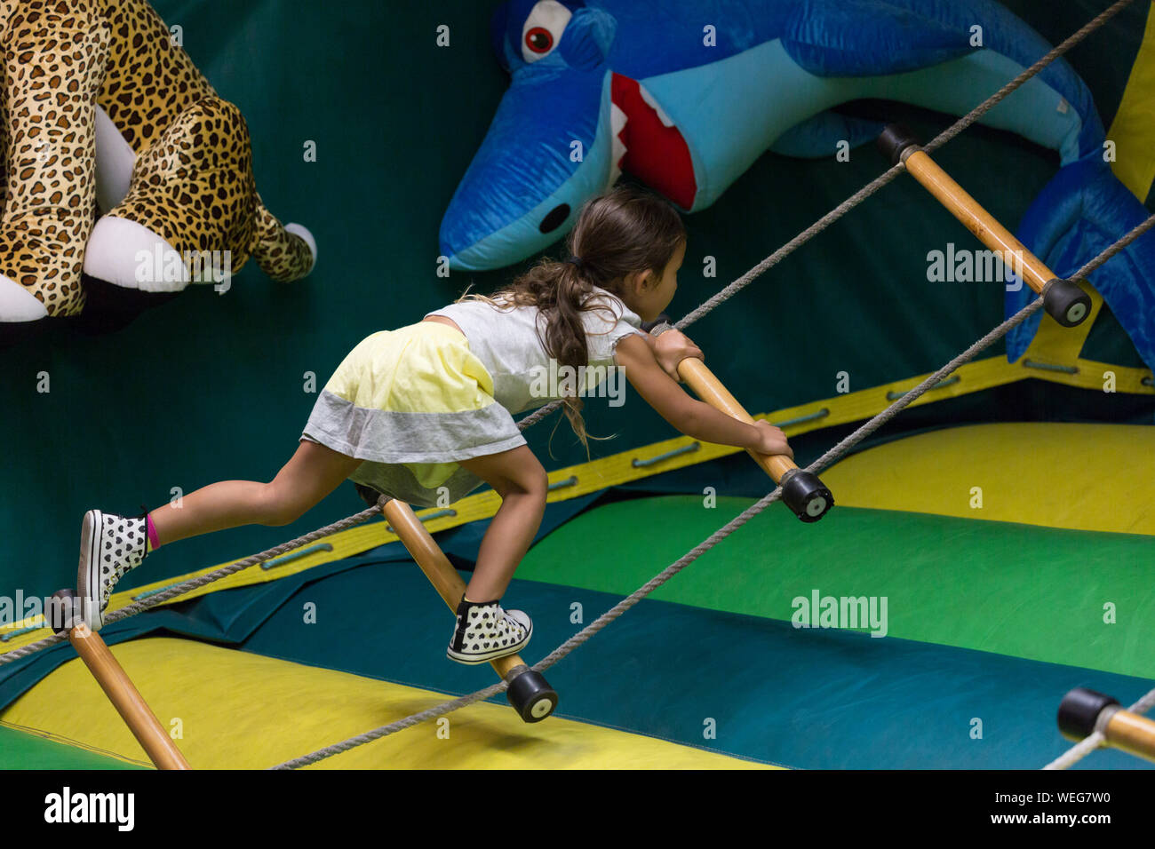 8-9 year old mixed ethnicity Asian girl on rope ladder in fairground, Santa Cruz, California Stock Photo