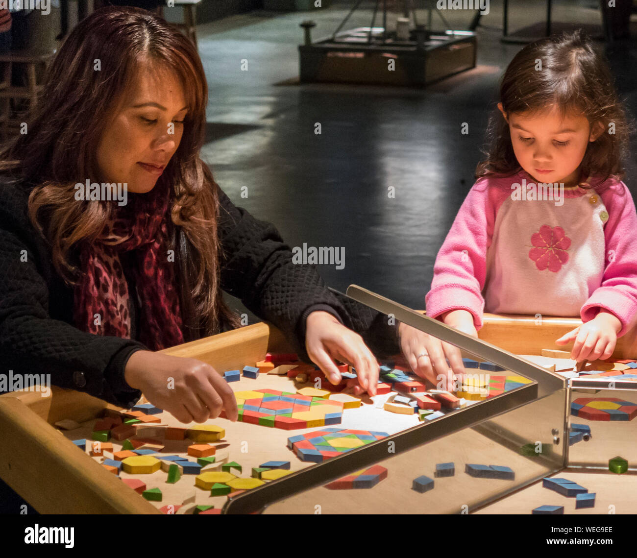 Mixed ethnicity mother and daughter involved in game at science museum