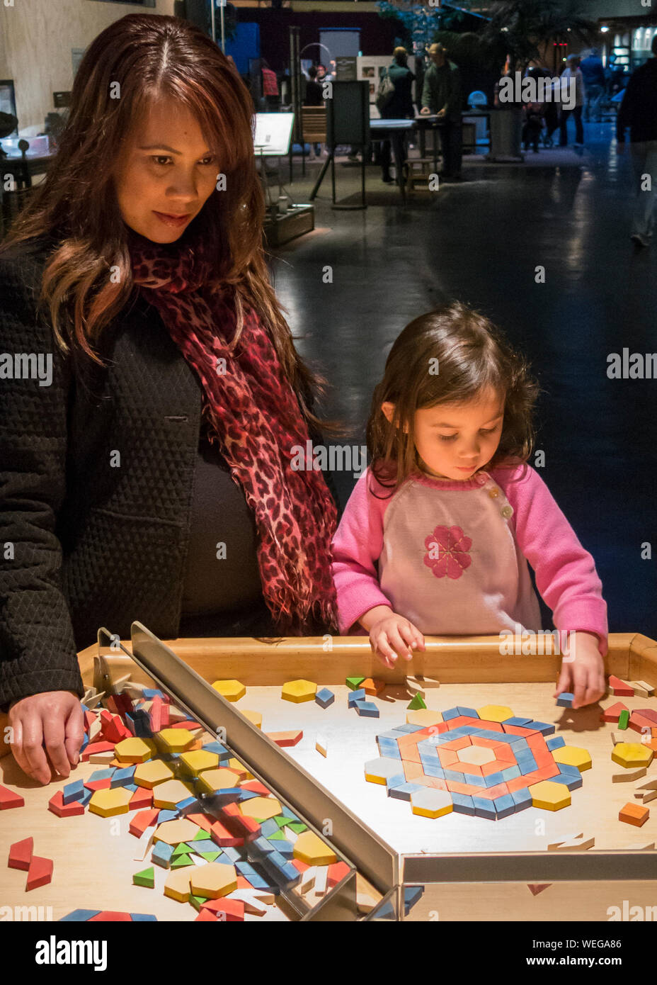 Mixed ethnicity mother and daughter involved in game at science museum