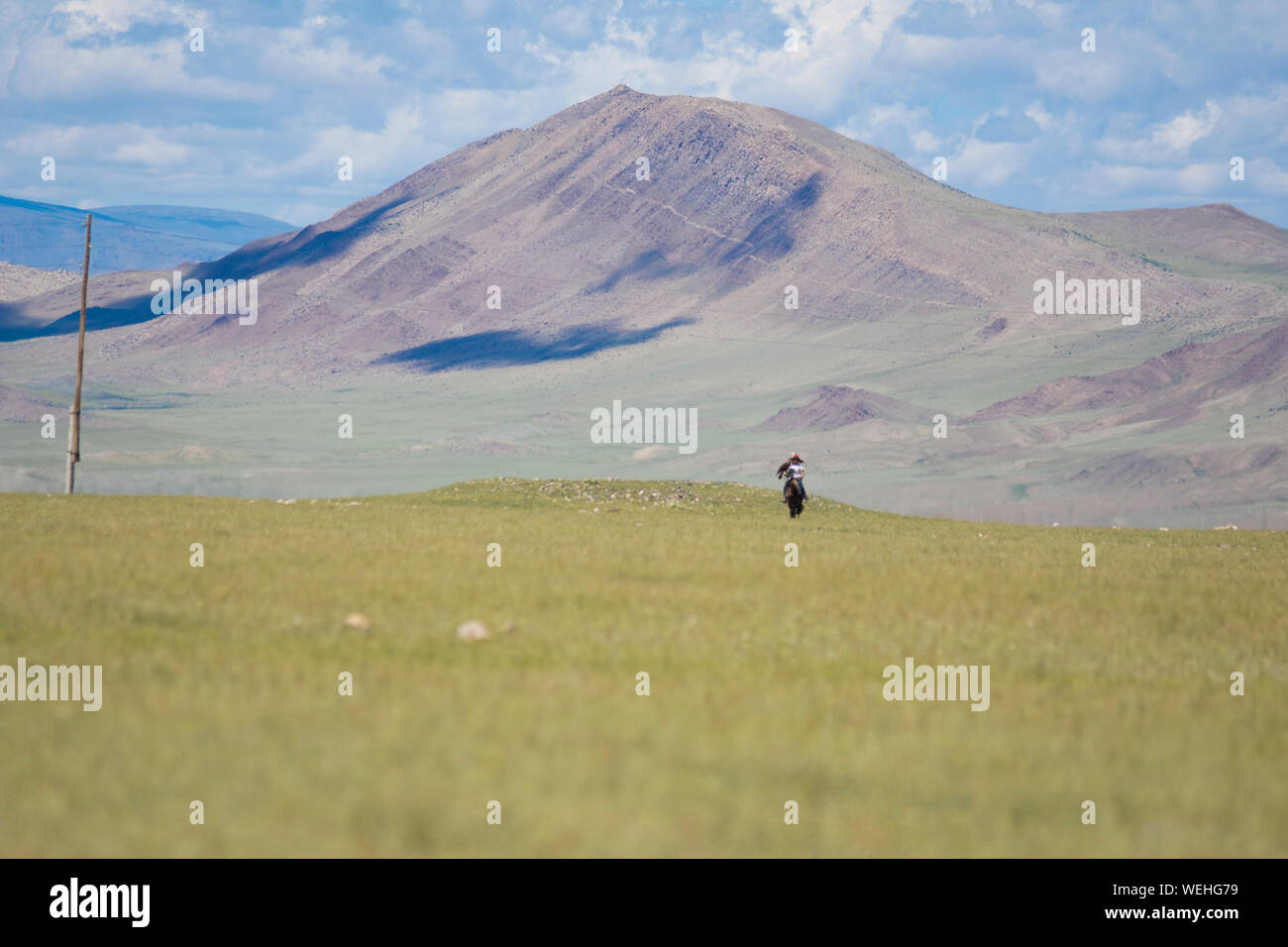 Kazakh eagle hunter on horse in Mongolian steppe Stock Photo