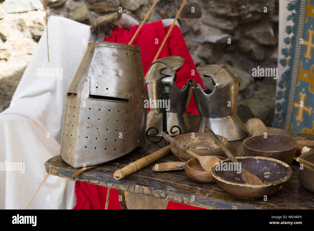 Medieval 12th century closed helmet or great helm and gauntlets with eating utensils in a re-enactment camp Stock Photo