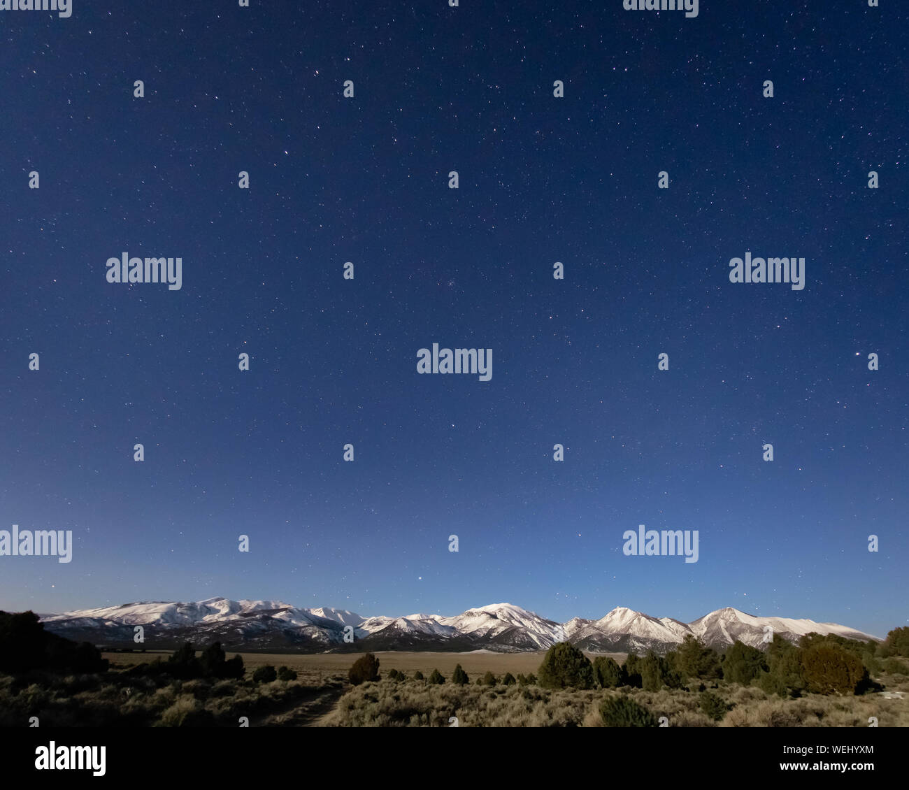 USA, Nevada, Lyon County, Sweetwater Range: Starry Skies above Snow Capped mountains on a bright full moon night. Views of Wheeler Peak, Mt Patterson, Stock Photo