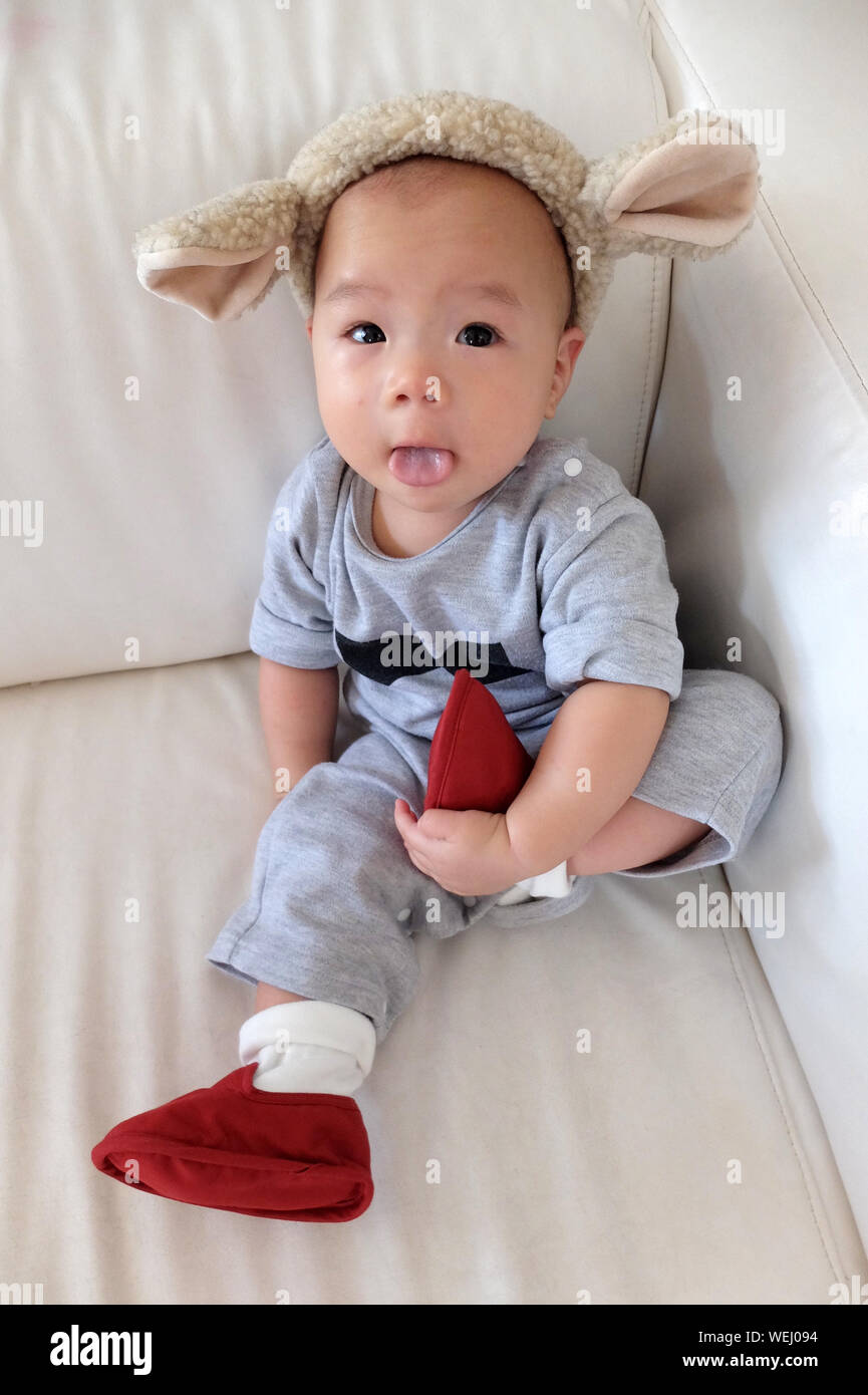 Full Length Portrait Of Baby Boy Sitting On Armchair At Home Stock