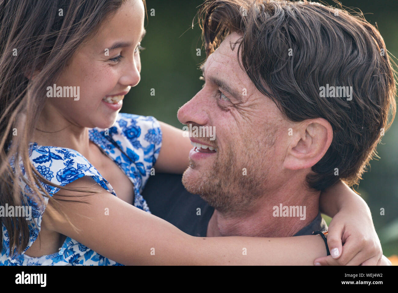 Caucasian father holding mixed ethnic Asian 9-year old daughter, both happy, San Jose, California Stock Photo
