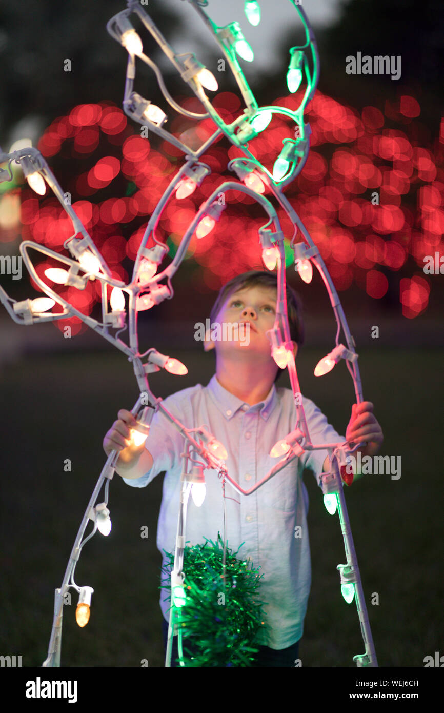 5 year old boy looking at Christmas lights at fairground at night Stock Photo