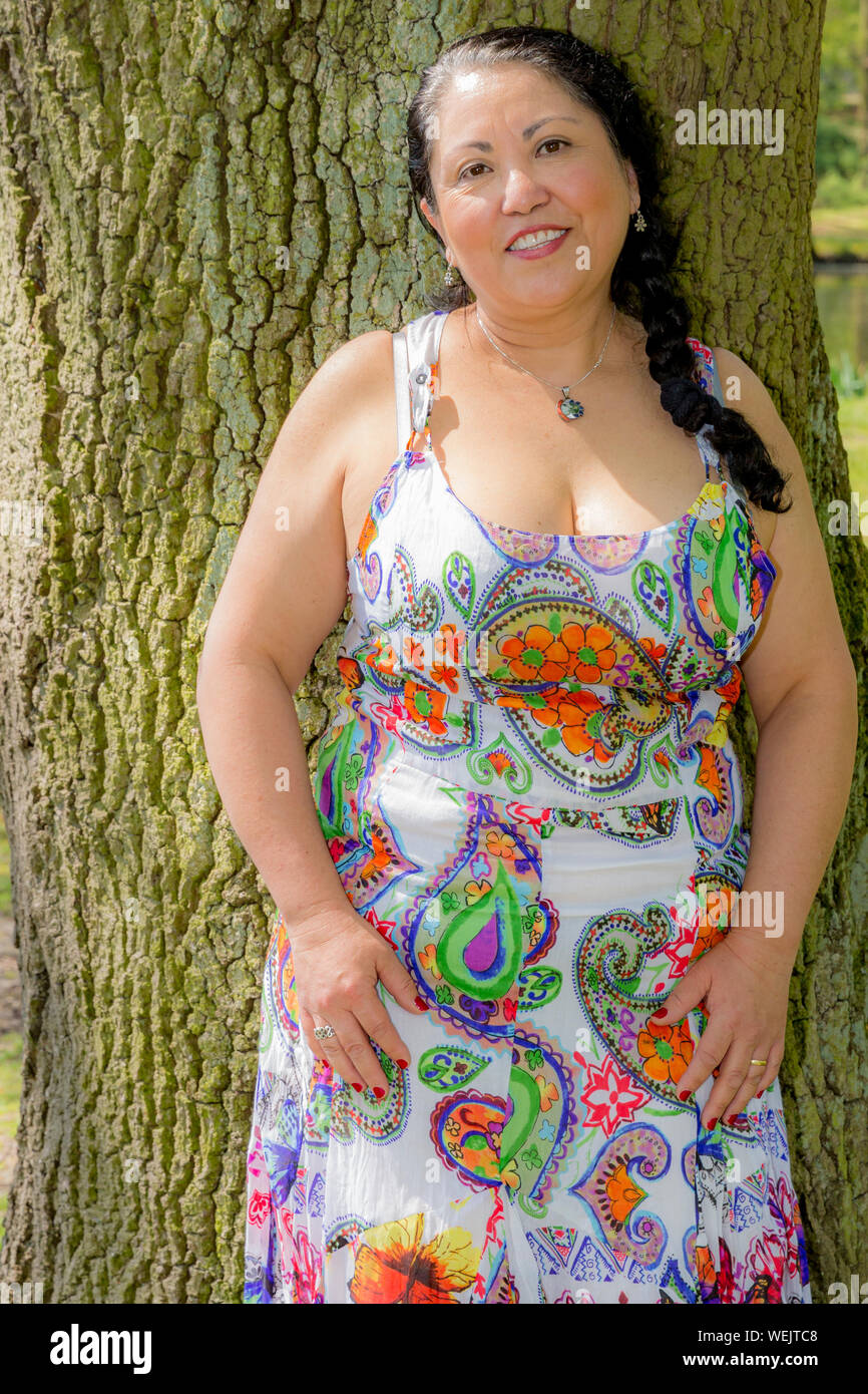 https://c8.alamy.com/comp/WEJTC8/beautiful-smiling-mexican-woman-leaning-on-a-tree-trunk-in-a-white-dress-with-multicolored-decoration-wonderful-sunny-day-in-the-netherlands-holland-WEJTC8.jpg