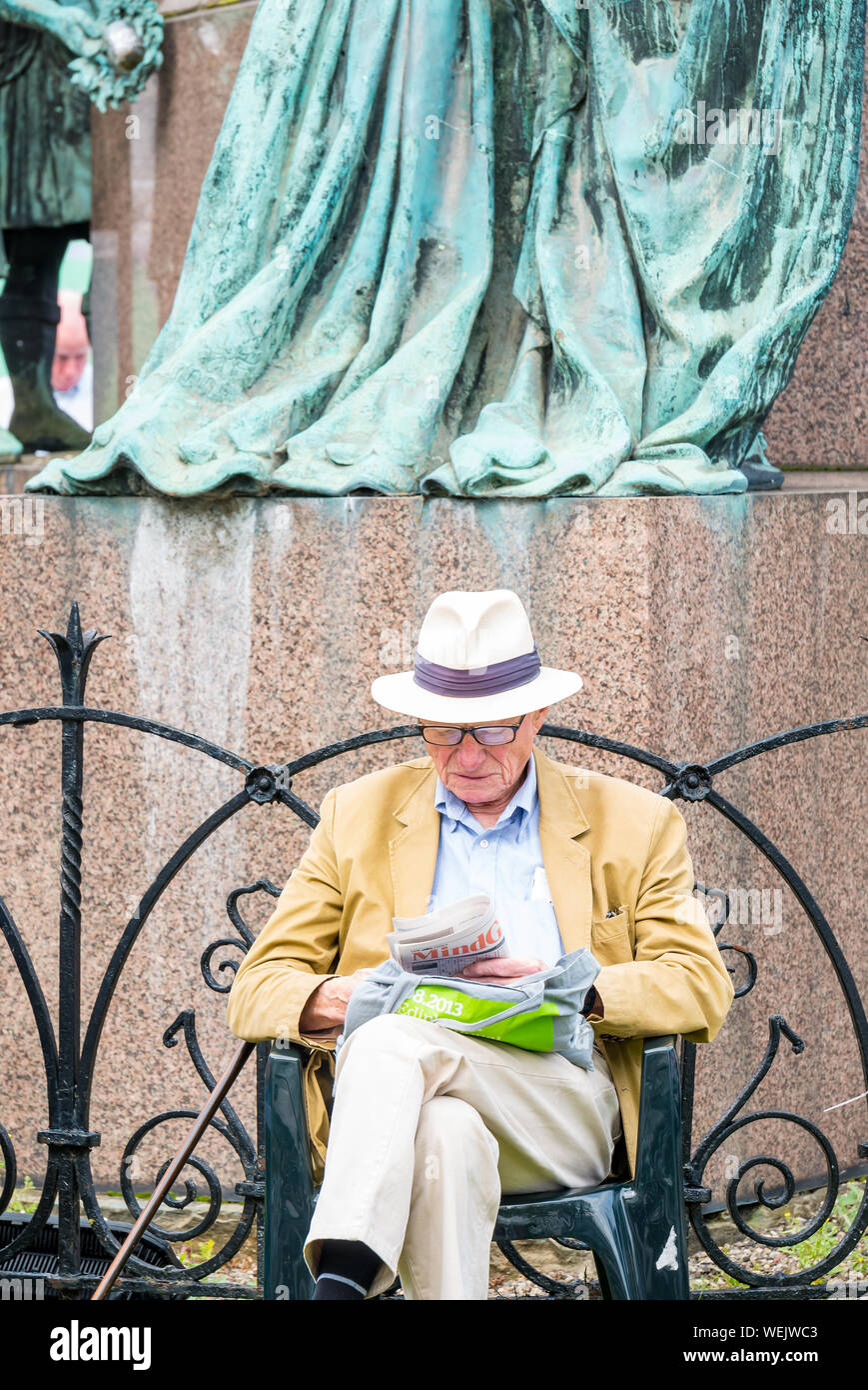 Man with Panama hat reading by sculpture during Edinburgh International Book Festival, Charlotte Square Garden, Scotland, UK Stock Photo