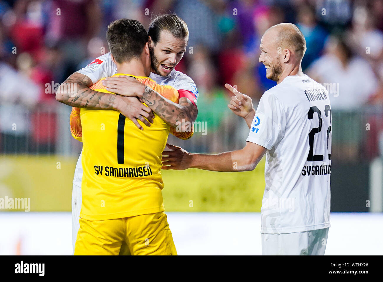 30 August 2019, Baden-Wuerttemberg, Sandhausen: Soccer: 2nd Bundesliga, SV Sandhausen - SV Darmstadt 98, 5th matchday, in Hardtwaldstadion. Sandhausen's goalkeeper Martin Fraisl (l-r), Sandhausen's Dennis Diekmeier and Sandhausen's Gerrit Nauber are happy about the victory after the end of the game. Photo: Uwe Anspach/dpa - IMPORTANT NOTE: In accordance with the requirements of the DFL Deutsche Fußball Liga or the DFB Deutscher Fußball-Bund, it is prohibited to use or have used photographs taken in the stadium and/or the match in the form of sequence images and/or video-like photo sequences. Stock Photo