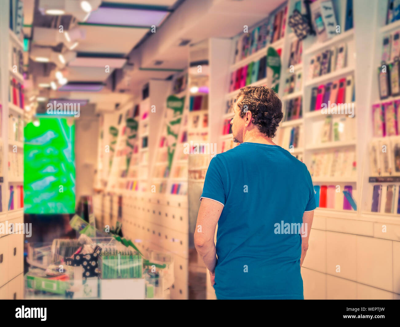adult man in a phone store choosing a colored cover to protect his smart phone Stock Photo