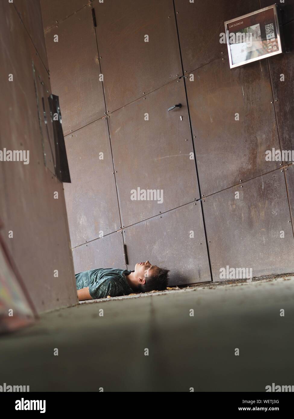 Surface Level Of Young Man Sleeping By Lockers In Room Stock Photo