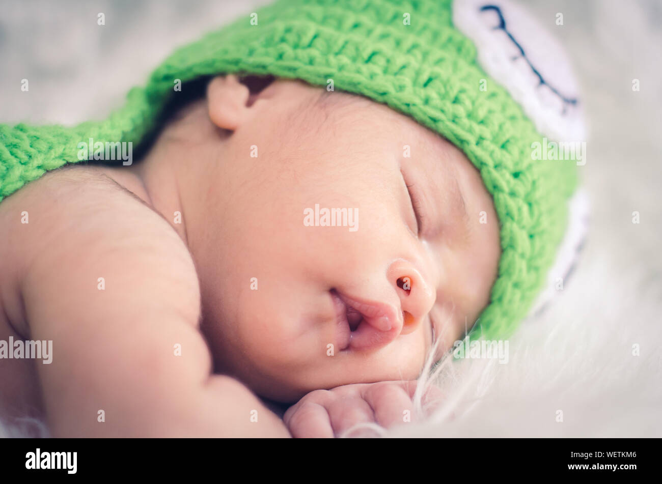 Close-up Of Cute Baby In Green Costume Sleeping On Fur Carpet Stock Photo
