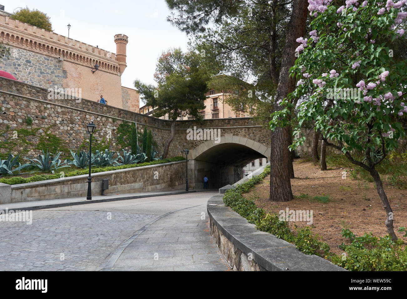 TOLEDO, SPAIN - APRIL 24, 2018: Picturesque street in toledo with cobblestoned bridge and view of the walls of the Alcazar. Stock Photo