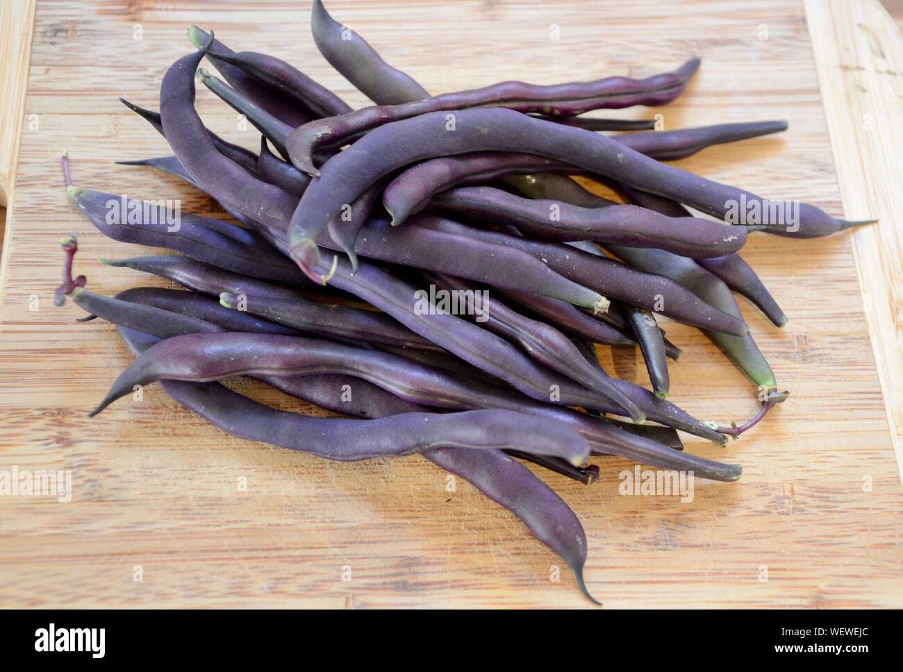 home grown purple beans on a wooden board in a london kitchen Stock Photo