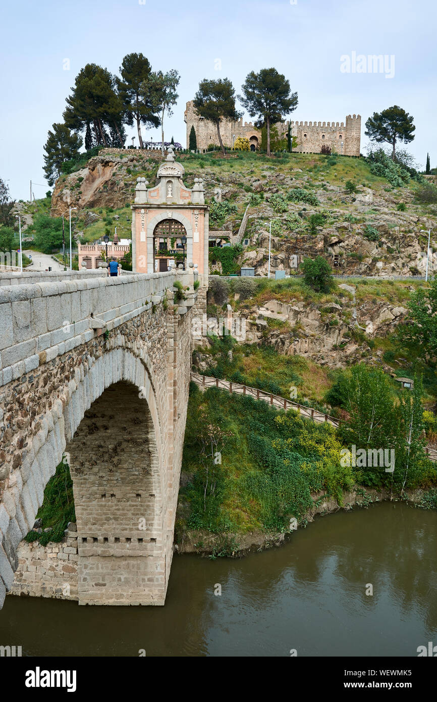 TOLEDO, SPAIN - APRIL 24, 2018: View of the baroque triumphal arch on the Alcantara Bridge over the Tagus River and the San Servando Castle in Toledo. Stock Photo
