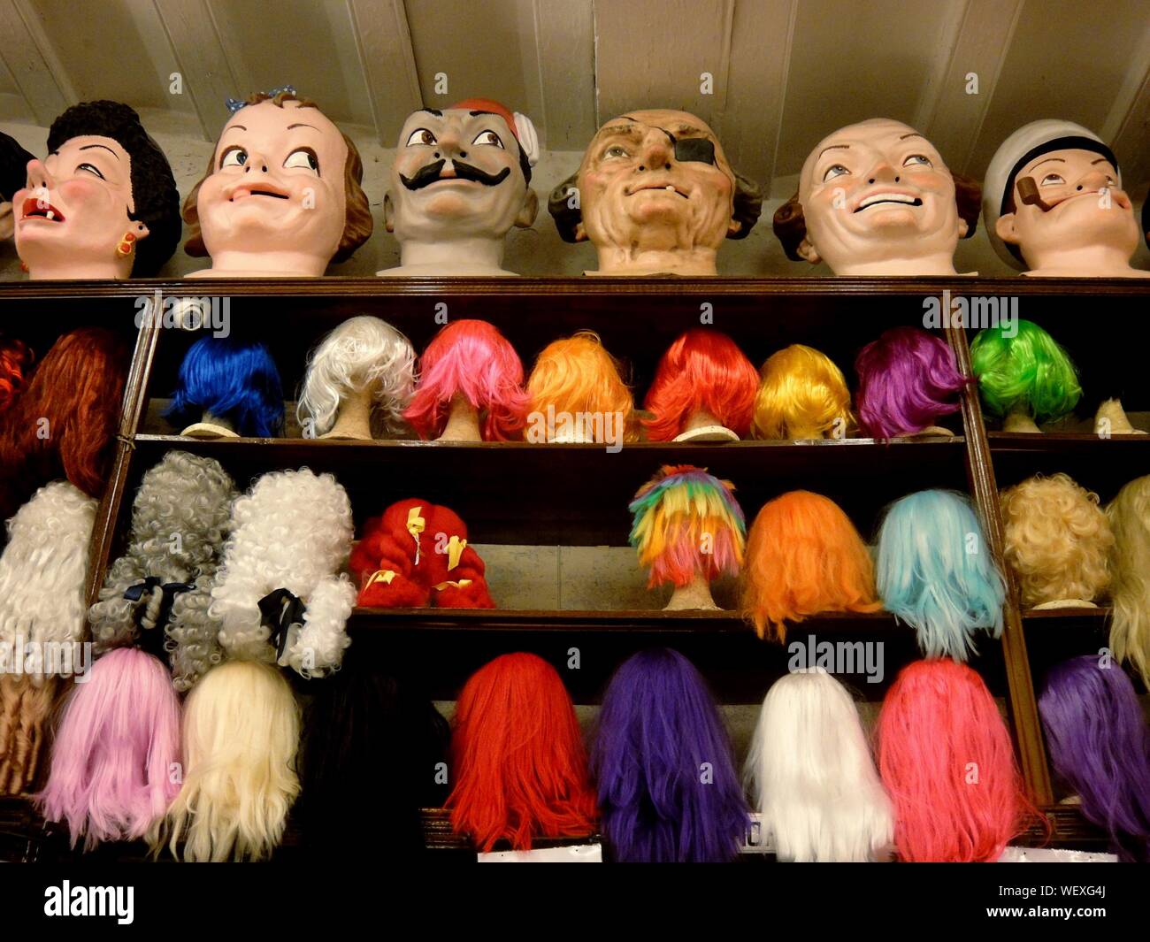 Low Angle View Of Colorful Wigs On Mannequin Heads Over Shelf At Store Stock Photo