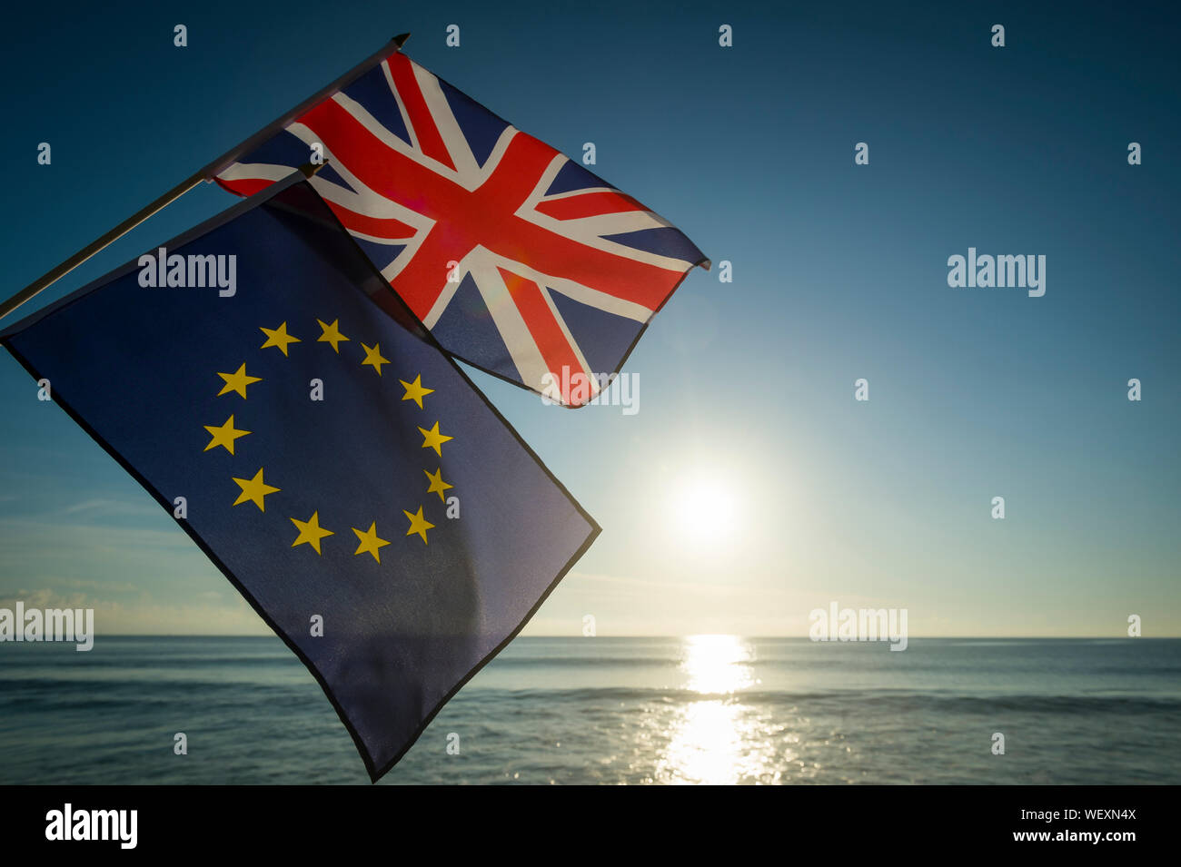 European Union and British Union Jack flags flying together as the sun rises on a new era on the relationship between the EU and UK after Brexit Stock Photo