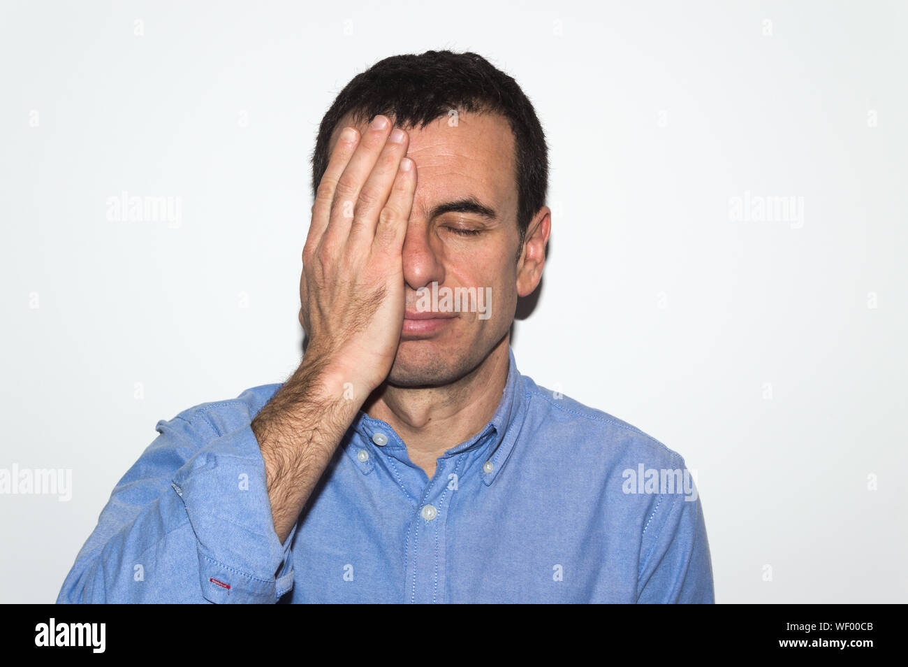 Man Covering Half His Face With Hand Against White Background Stock
