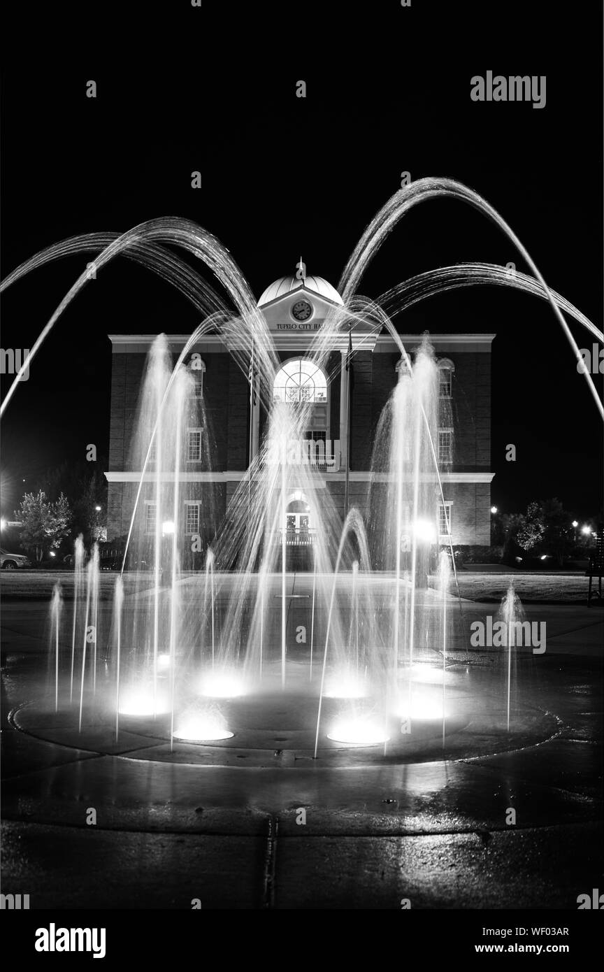 A night time view of Tupelo City Hall Building with water spout