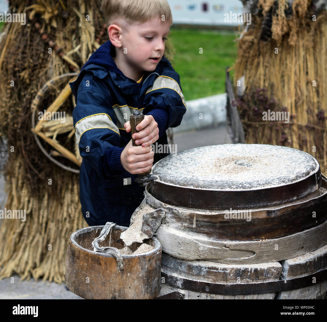 Boy Grinding Flour On Millstones Stock Photo
