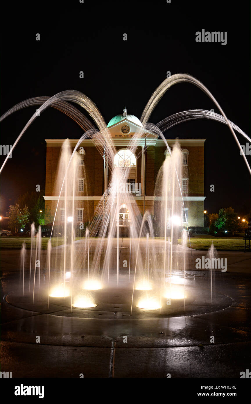 A night time view of Tupelo City Hall Building with water spout fountain feature with lights in foreground,  in Elvis hometown, Tupelo, MS, USA Stock Photo