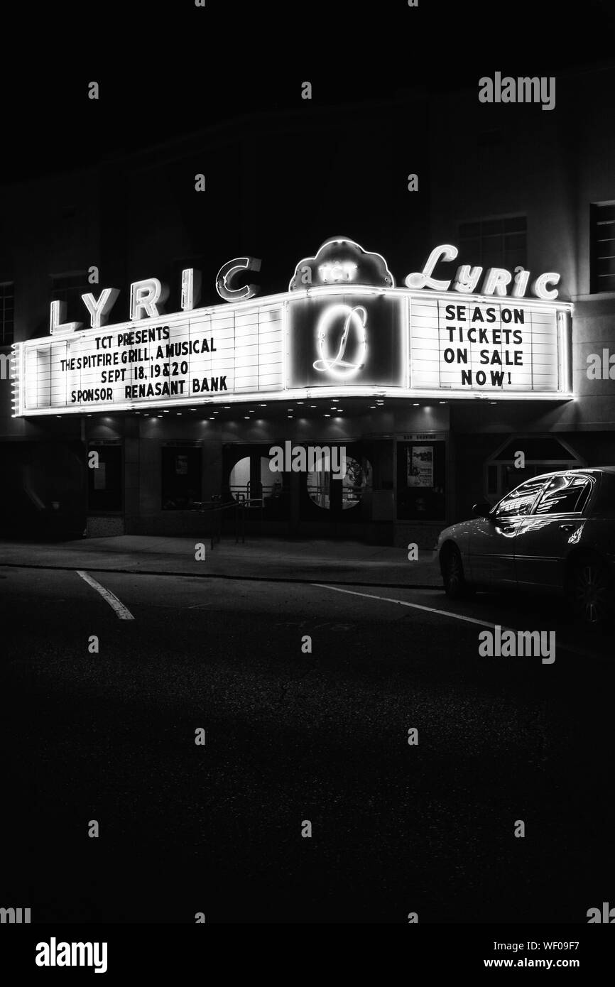 A nostalgic view of a vintage movie theater, The Lyric,  with neon marquee and reflections off of cars in dark night time scene in Tupelo, MS, USA Stock Photo