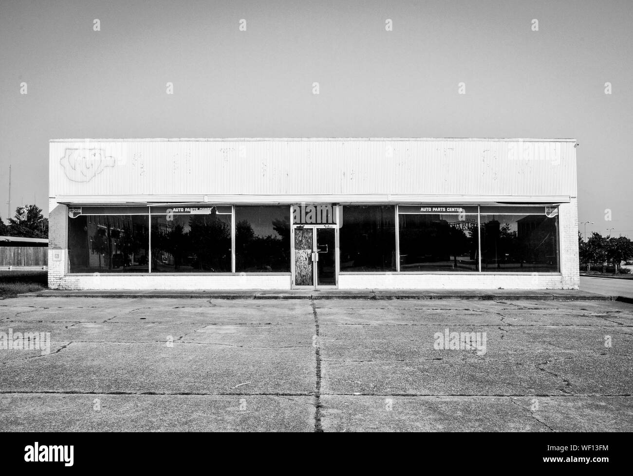 Abandoned old white commercial building in distress, once an Auto Parts center, in an empty parking lot, in an economically depressed area of America Stock Photo