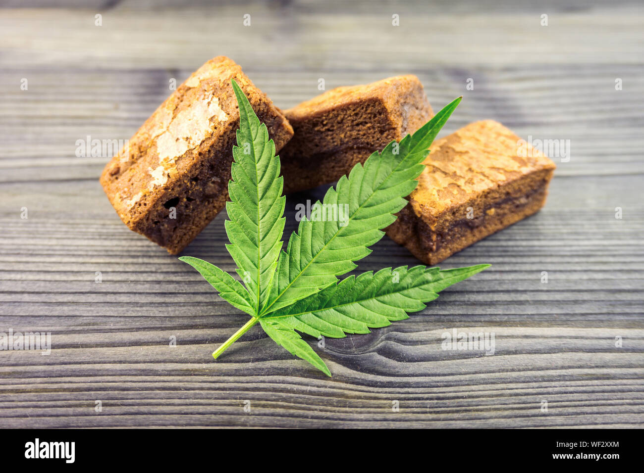 Cannabis Hash brownies with cannabis leaf on wooden table Stock Photo