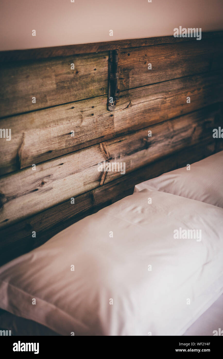Pillows On Bed Against Wooden Headrest At Home Stock Photo
