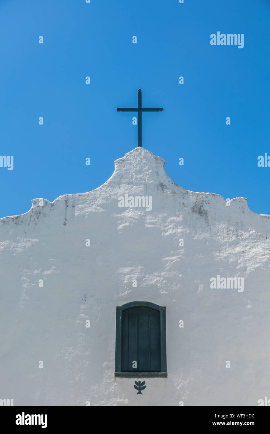 Closeup and detailed upwards view of the white facade of the antique and humble Quadrado church, at Trancoso, Porto Seguro, Bahia, with a simple woode Stock Photo