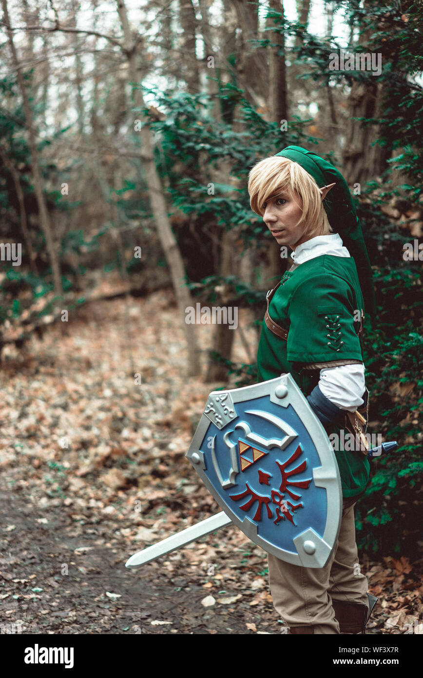 Download Side View Of Young Man In Elf Costume With Sword And Shield Standing At Forest Stock Photo Alamy