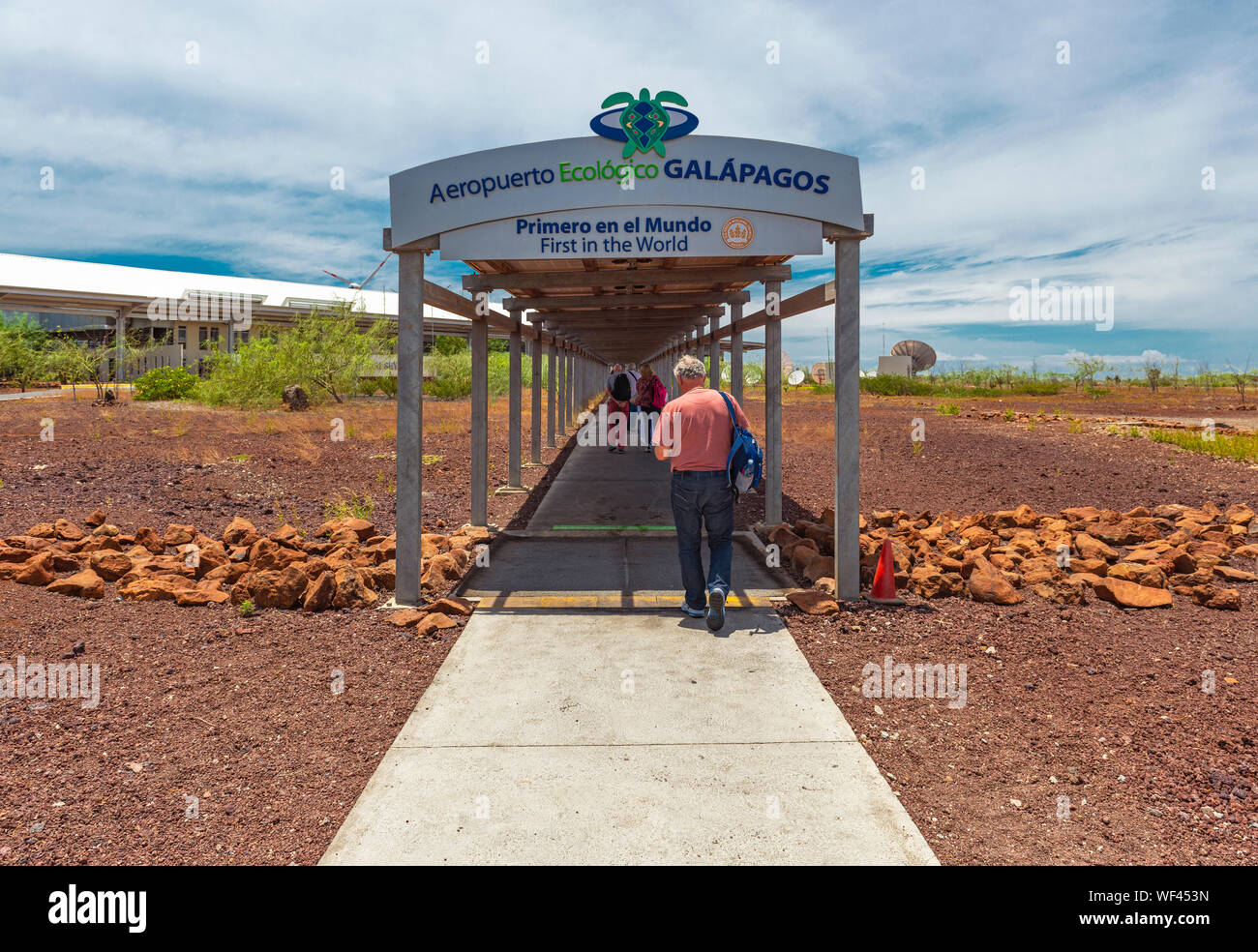 Tourists walking to the Ecologic Airport building of the Galapagos Islands on Baltra island, working on solar and wind energy, Ecuador. Stock Photo