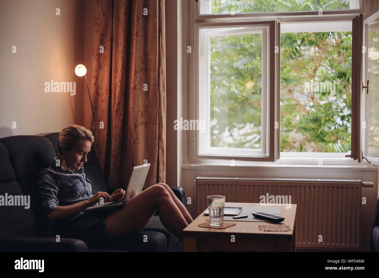 Woman Using Laptop In Living Room Stock Photo