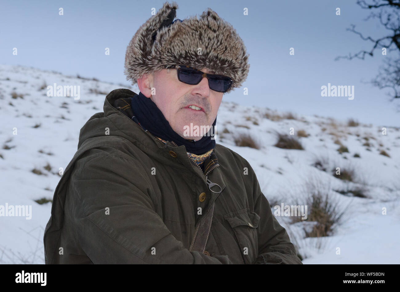 Man Wearing Fur Deerstalker Hat While Standing On Snowy Field Stock Photo
