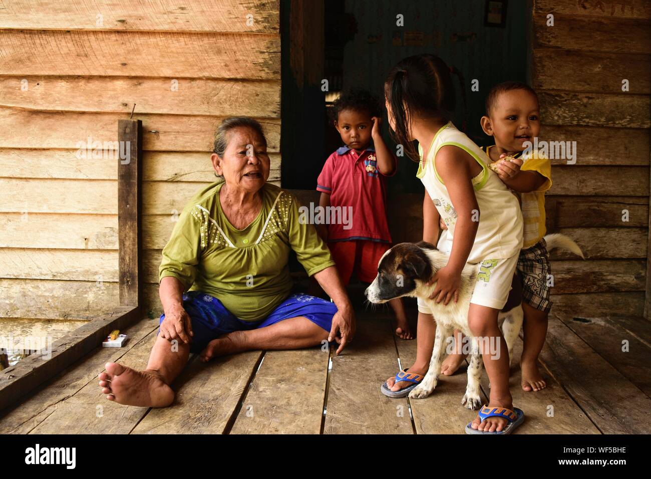 Grandmother With Grandchildren Sitting At Doorway Stock Photo